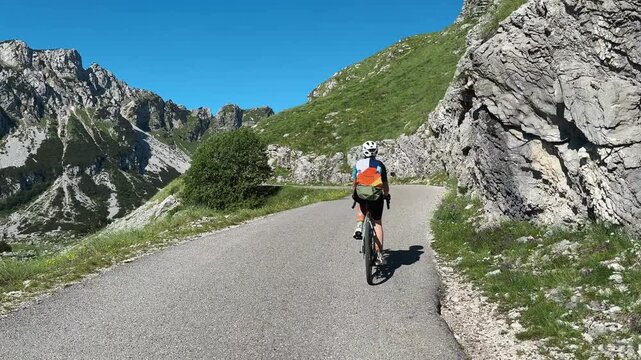 Female cyclist rides along Sedlo Pass in Durmitor National Park, Montenegro, surrounded by dramatic limestone cliffs and alpine scenery