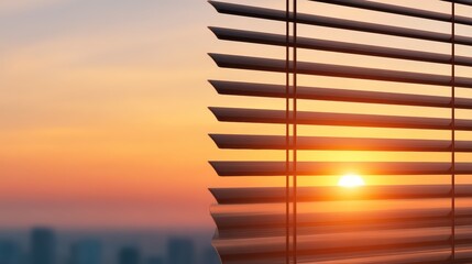 A vibrant sunset viewed through partially closed window blinds, casting warm light and shadows indoors.