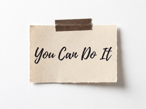 Torn paper note with handwritten text is affixed to a white surface with adhesive tape