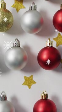 Animation of snow falling over christmas baubles and stars