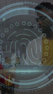 Animation of cyber security text, thumbprint icon, diverse coworker discussing over laptop in office