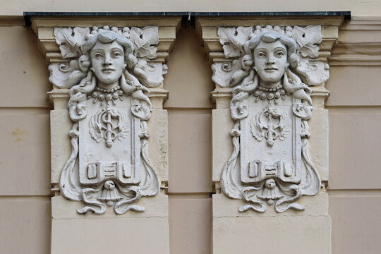 Art Nouveau architectural reliefs featuring female mascarons and caduceus symbols on building facade