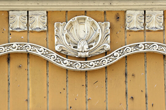 Ornate architectural relief ornament with shell motif on yellow wooden facade
