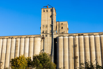 Old concrete grain elevator storage silos under clear sky © SNEHIT PHOTO