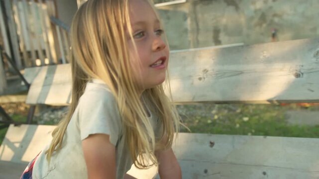 Boy in golden hour portrait near weathered building with swing set in background