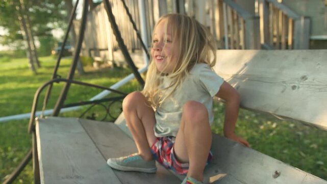 Boy in golden hour portrait near weathered building with swing set in background