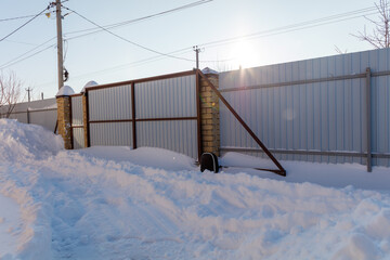 Naklejka premium Snowy fence stands beside deep winter snowbank