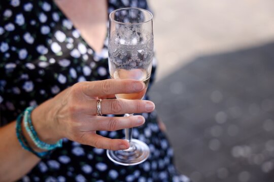 Main d&rsquo;une femme tenant une fl&ucirc;te de vin effervescent en ext&eacute;rieur