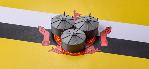 Liquefied gas storage tanks set against the Brunei flag, representing the concept of supply © chernikovatv