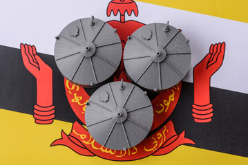 Liquefied gas storage tanks set against the Brunei flag, representing the concept of supply © chernikovatv