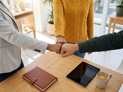 Diverse business professionals bumping fists to signify teamwork and unity during a productive morning office meeting