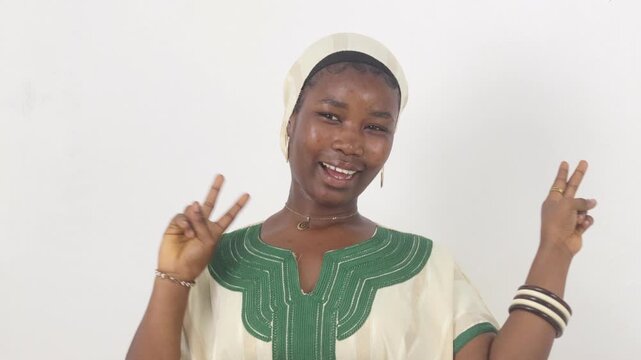 A cheerful young African woman makes a victory sign with both hands