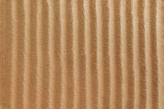 Close-up of brown corrugated cardboard surface with broad vertical ridges and natural fibrous paper texture