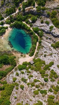 Aerial view of the Cetina River spring in Croatia, a deep karst water source surrounded by rocky landscape and lush greenery