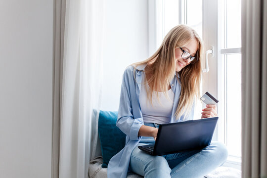 Shopping online at home. Woman paying with laptop by credit card for delivery purchases. Happy girl buy insurance, investing. Technology lifestyle for finance, e-commerce