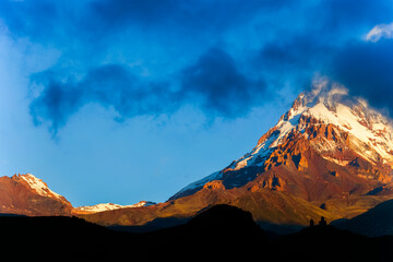 Fototapeta premium Scenic sunrise alpine landscape over Kazbek mountain volcano in Kazbegi, Stepantsminda, Georgia