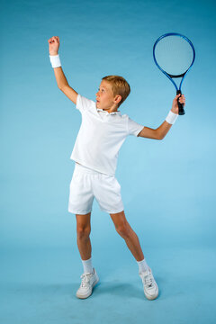 Young male tennis player dressed all in white practicing his serve