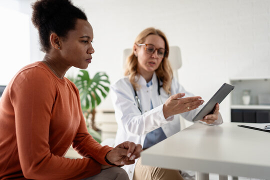 Female doctor explaining medical test results on a digital tablet to a concerned mature woman during a healthcare consultation