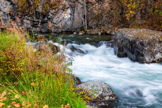Rushing river water flowing over rocks in autumn