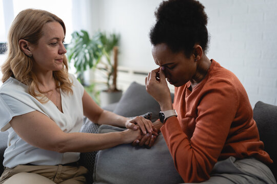 Caring therapist reaching out to comfort an emotional woman, representing empathy, compassion and trust in psychotherapy