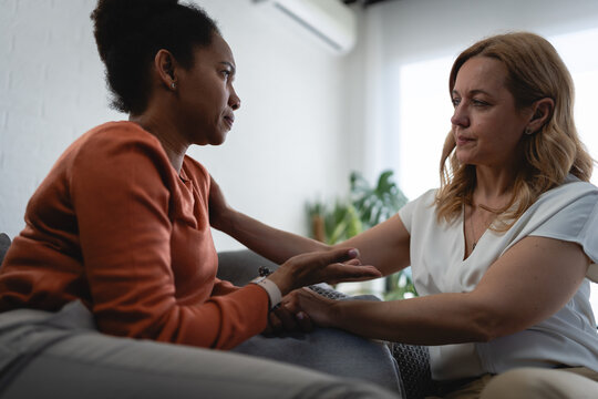 Compassionate female therapist holding a woman's hands and comforting her during an emotional counseling session