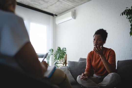 Troubled woman seeking professional emotional support while discussing personal difficulties with a counselor during a private session.