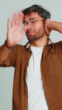 Don't want to hear and listen. Frustrated annoyed irritated Indian young man covering ears gesturing no, avoiding advice ignoring unpleasant noise loud voices. Arabian guy isolated on gray background