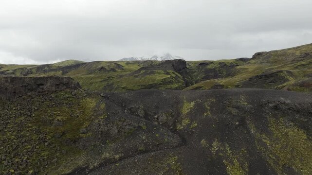Stunning aerial drone footage of the rugged volcanic landscape on Iceland, showcasing a hiker on the famous Laugavegur hiking trail. Drone booms up and pushes in for a wider view.