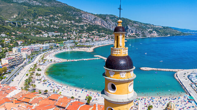 Aerial drone view of the bell tower of the Basilica of Saint-Michel in front of Sablettes Beach in Menton on the coast of the Mediterranean Sea in the French Riviera