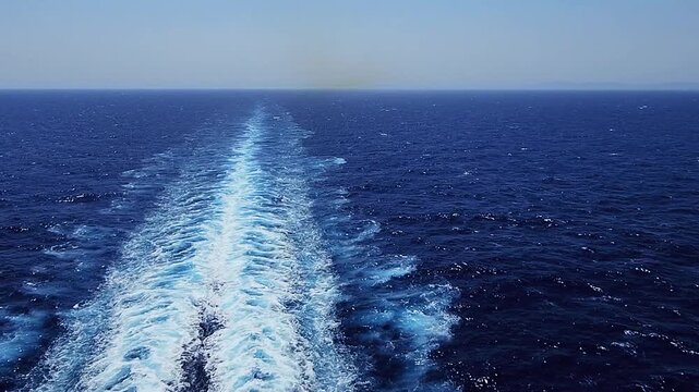 Ocean wake stretching across sea behind passenger cruise liner during summer voyage. Handheld