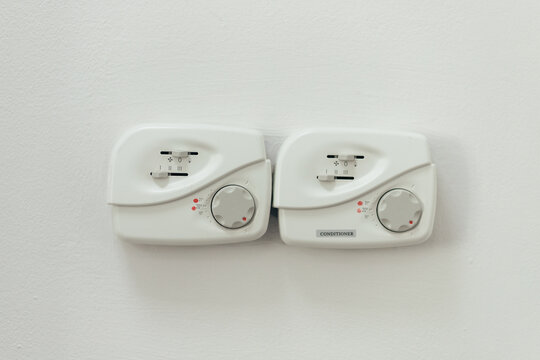 Pair Of White Climate Control Panels Mounted On Wall. Dual Zone Thermostats Display Temperature Settings And Indicator Lights.