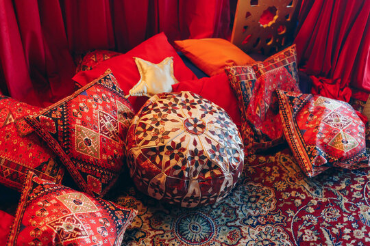Colorful Oriental-Style Pillows And Pouf Create Cozy Bohemian Seating Area. Traditional Decorative Cushions With Ornate