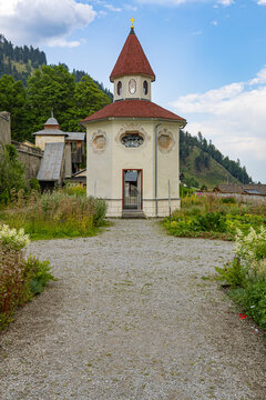 Exterior view of the small octagonal chapel with a red-tiled roof and lantern tower set along a gravel pathway in Maria Luggau, Lesachtal, Carinthia, Austria