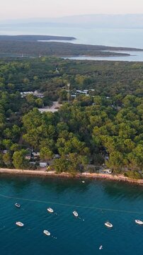 FKK Naturist Baldarin Campsite In Punta Kriza On Cres Island, Croatia, Filmed By Drone During A Beautiful Summer Evening. Aerial Views Show Campervans, Motorhomes, Coastal Nature at Sunset