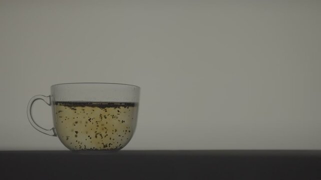 Slow Motion Tea Leaves Infusing in Hot Water in Transparent Cup_Medium