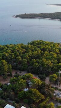 FKK Naturist Baldarin Campsite In Punta Kriza On Cres Island, Croatia, Filmed By Drone During A Beautiful Summer Evening. Aerial Views Show Campervans, Motorhomes, Coastal Nature at Sunset