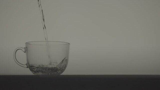 Slow Motion Pouring Hot Water into Transparent Cup with Bubbles