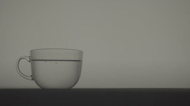 Slow Motion Tea Leaves Infusing in Hot Water in Transparent Cup_Less