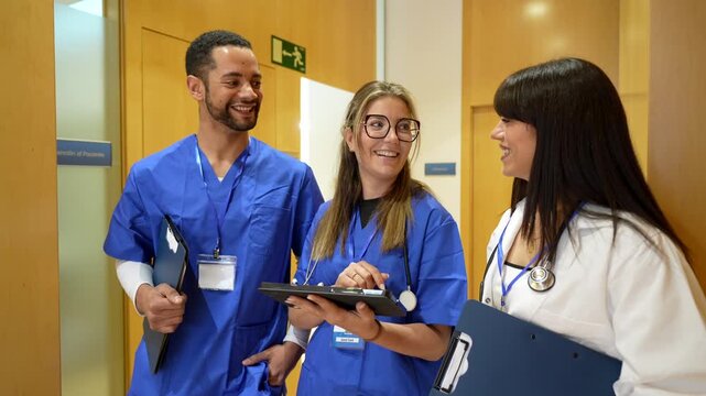 Professional group of a doctor and two nurses discussing a patient's diagnosis using a digital tablet while walking through the hospital hallway. Showcasing teamwork and modern healthcare technology