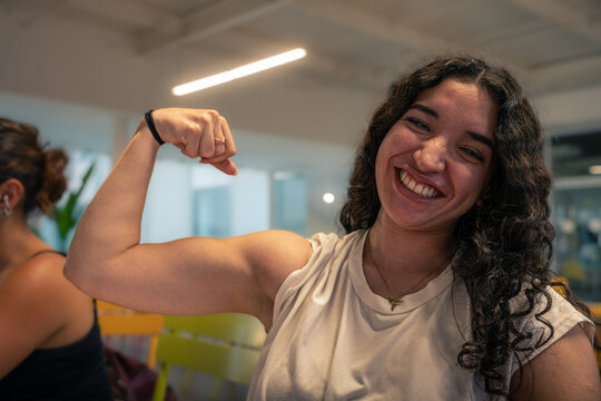 Young woman flexing biceps showing strength and confidence