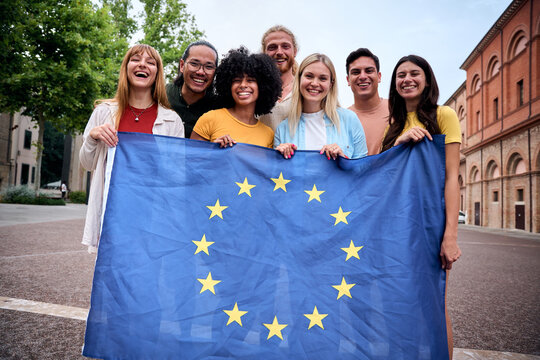 Multiracial group of friends holding the European Union flag with pride, symbolizing unity and diversity. Joyful atmosphere outdoors, promoting togetherness and cultural harmony in a vibrant setting