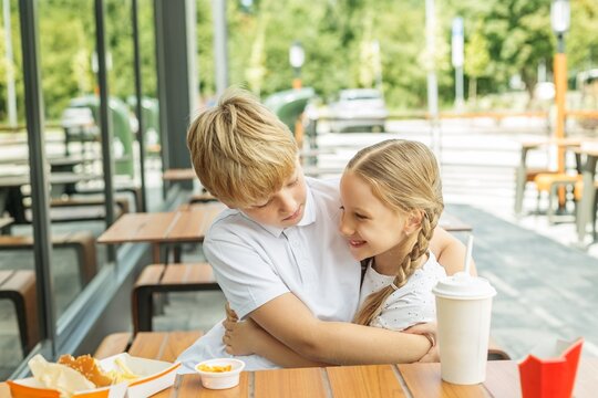 Happy siblings hugging during fast food meal