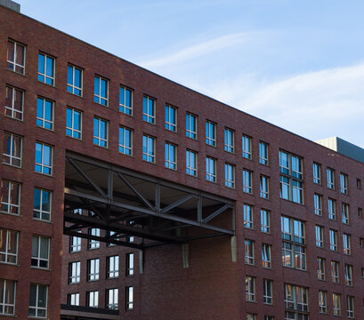 Modern brick building facade featuring many windows and a connecting skybridge structure
