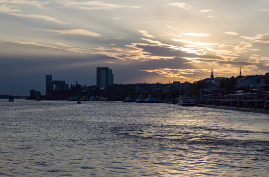 Hamburg city skyline with boats on Elbe river during a colorful sunset