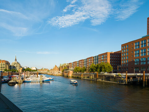 Hamburg canal displaying historic architecture, boats, and a city skyline under a clear sky