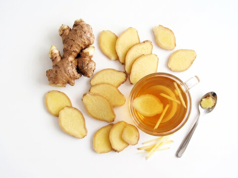 Cup of healthy hot ginger tea with fresh raw ginger root isolated on white background