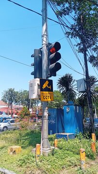 Traffic Light Showing Red with CCTV Surveillance Warning Sign on Urban Street Pole in Indonesia