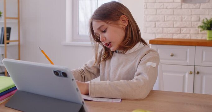 Online tutoring classes for small child learning, student boy e-learning on distant study online with tablet, sitting at table, developing child on weekend at home, using platform for private lesson