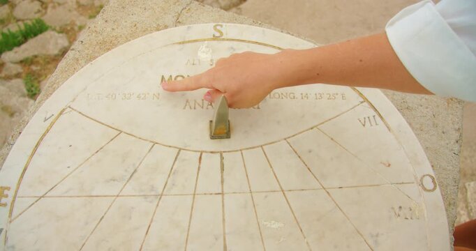 A hand points at markings on a marble sundial engraved with Monte Solaro in Capri Italy