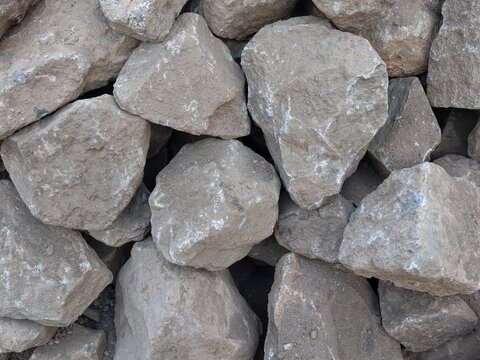 A dense arrangement of heavy weathered grey boulders stacked together for heavy construction purposes and durable landscaping projects creating a sturdy barrier for erosion control